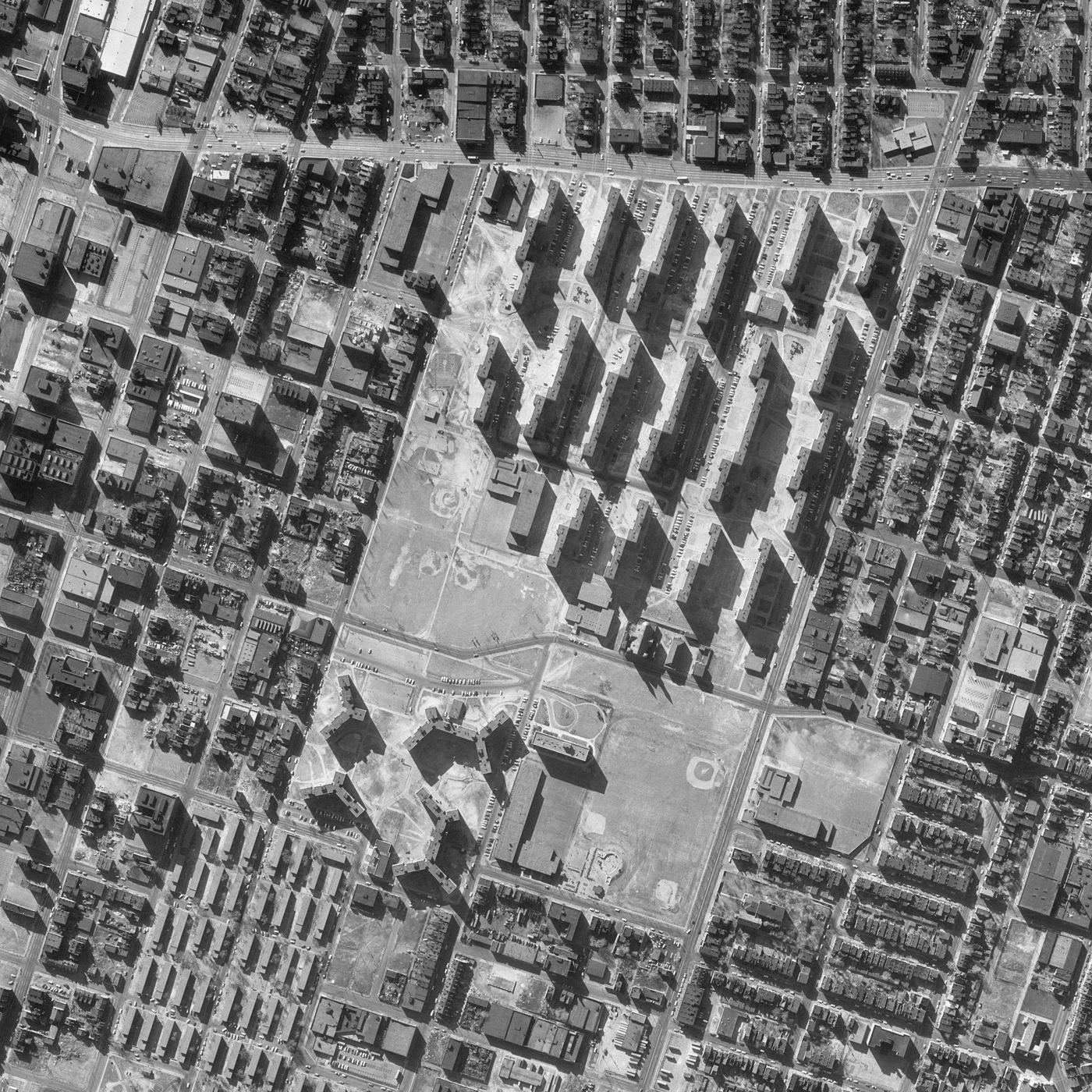 Black and white overhead aerial photo, March 1968, cropped to Pruitt-Igoe: rows of identical slab towers casting long shadows on a cleared site